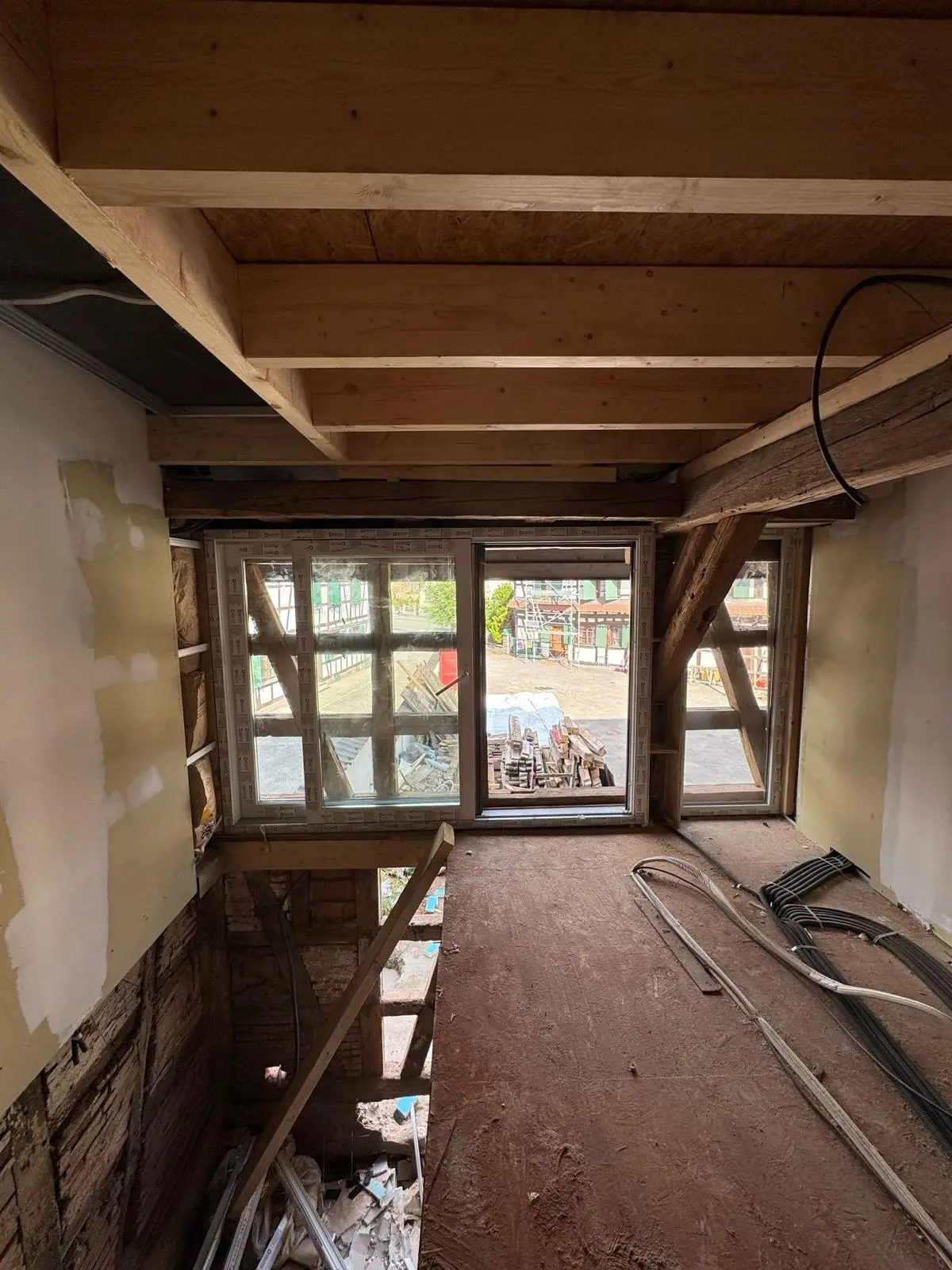 Fenêtres PVC posées dans un mur à pans de bois, sous un solivage neuf ; finitions et sol encore à faire