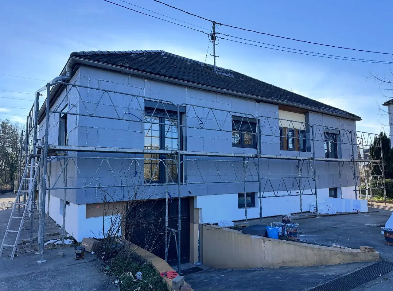 Panneaux isolants posés sur la façade sous échafaudage : isolation par l’extérieur en cours, enduit de finition à faire